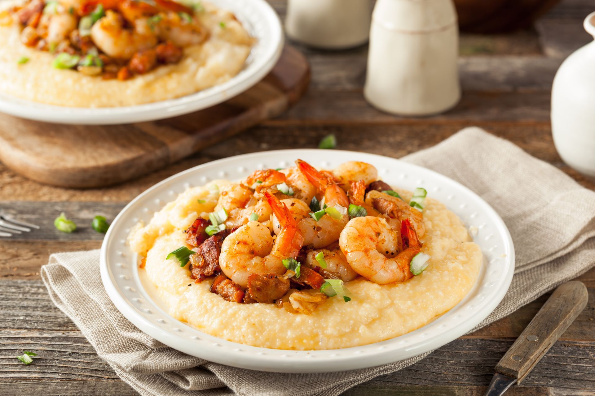 A white plate topped with shrimp and grits on a wooden table.