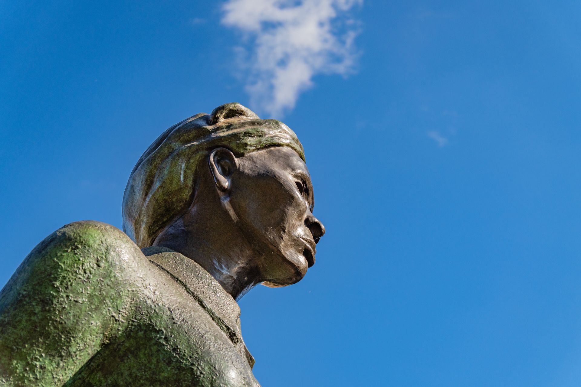 A statue of a man with a blue sky in the background.