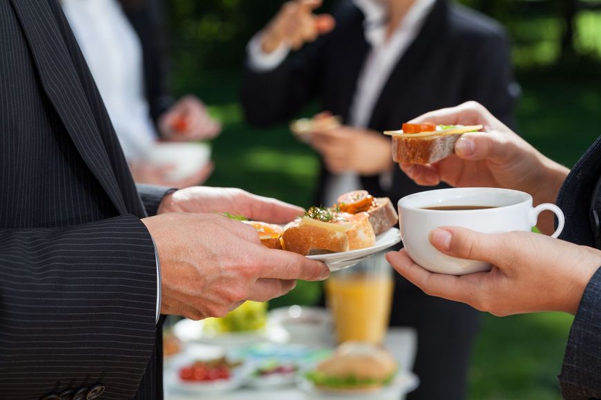 A man is holding a cup of coffee and a plate of food.
