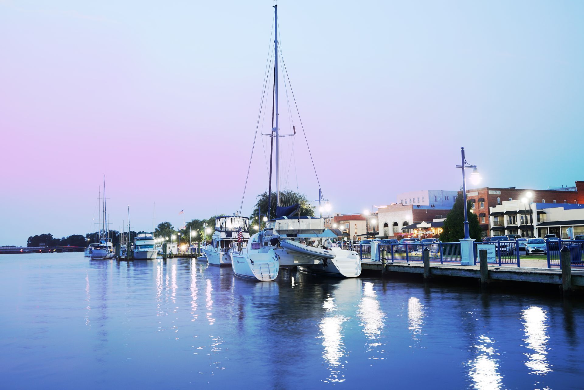 A row of boats are docked in a harbor at night