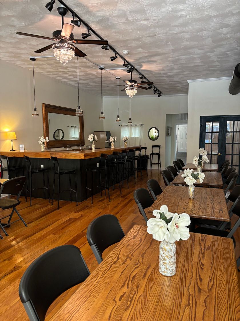 Elegant dining room with wooden tables, black chairs, and white floral centerpieces under ceiling lights