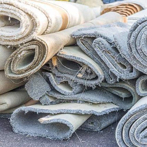 A pile of rolled up carpets on the ground.
