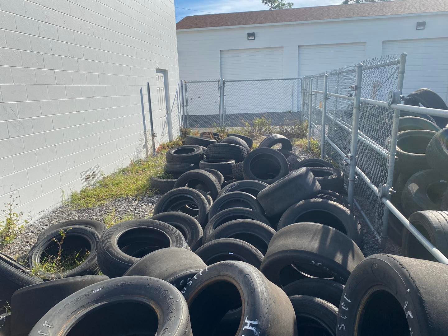 A bunch of tires are stacked on top of each other in front of a building.