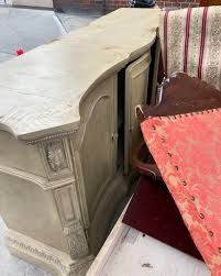 A bunch of furniture is sitting on the ground on the sidewalk.