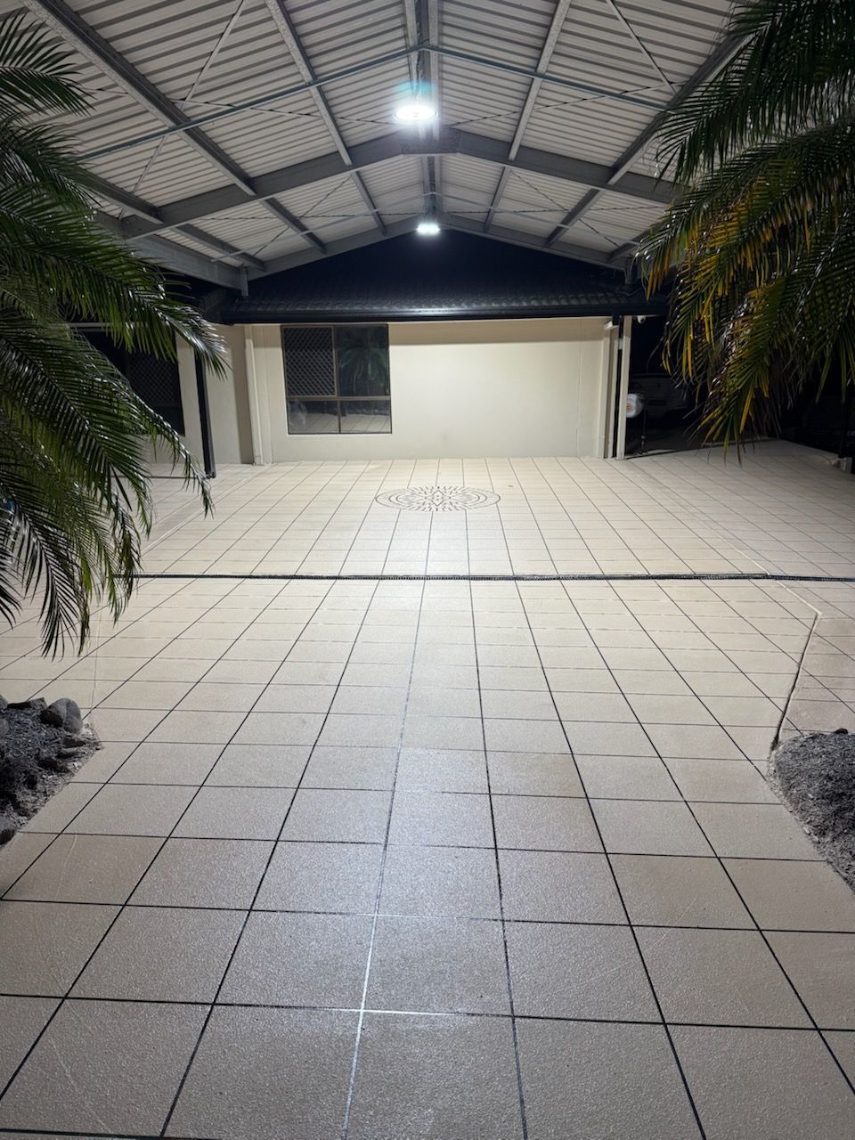An undercover concrete floor with two palm trees 