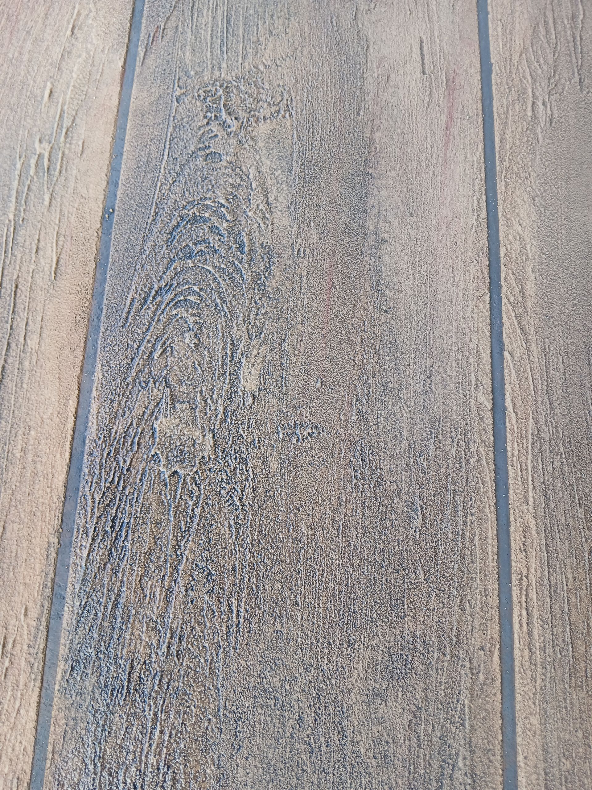 close up of concrete with a brown wood plant finish — Troys Concrete Overlays in Hillcrest, QLD