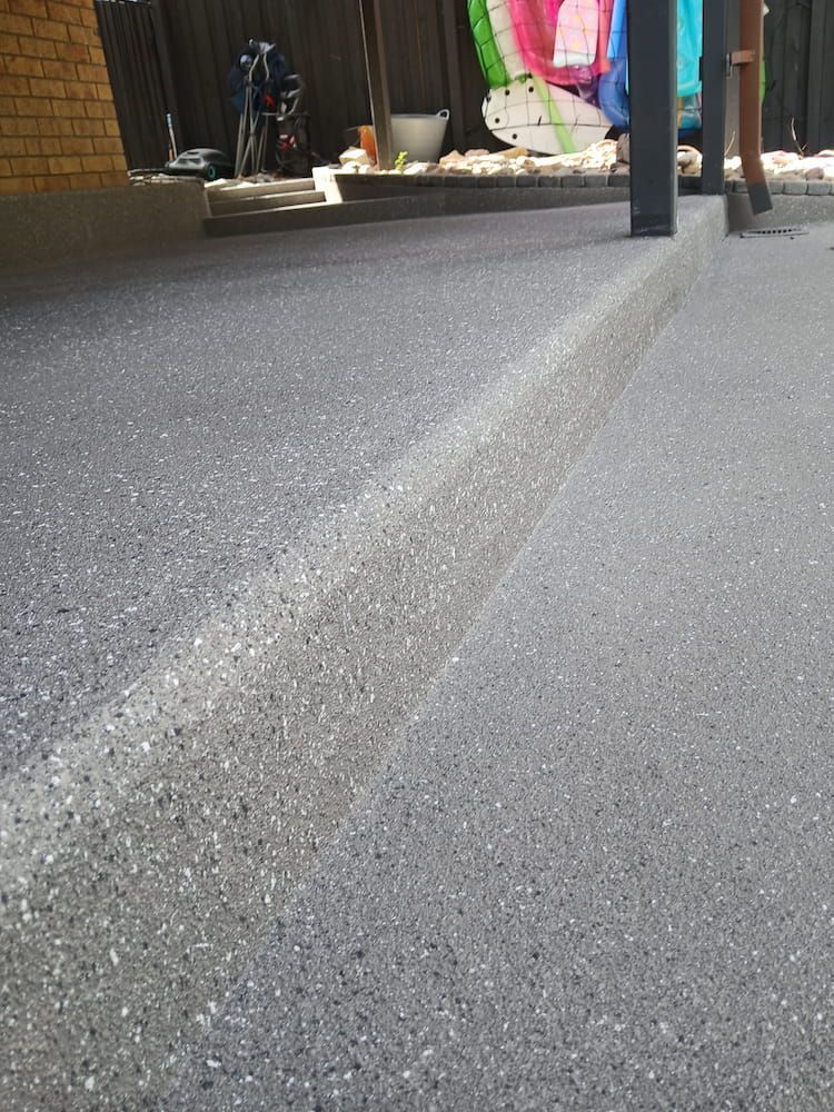 A Close Up of a Concrete Floor With a Fence in the Background — Troys Concrete Overlays in Hillcrest, QLD