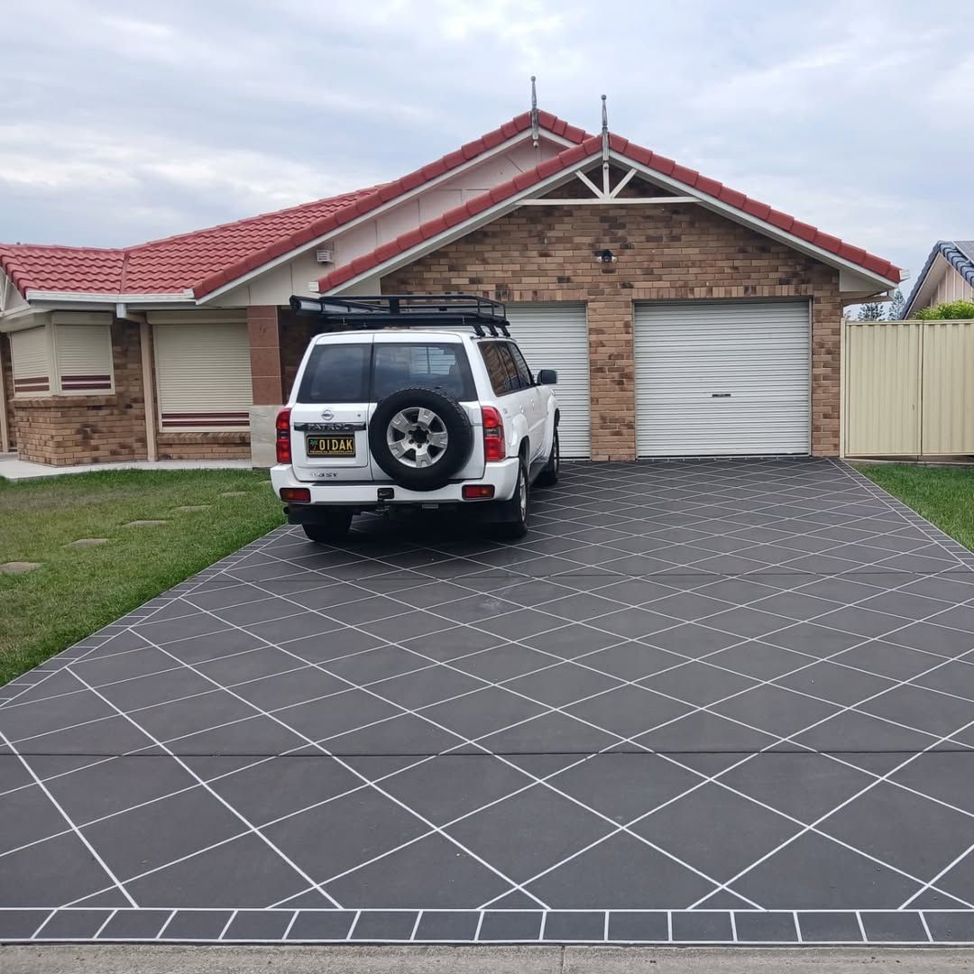 Suburban house with red roof, white SUV in driveway, and gray patterned pavement in front.