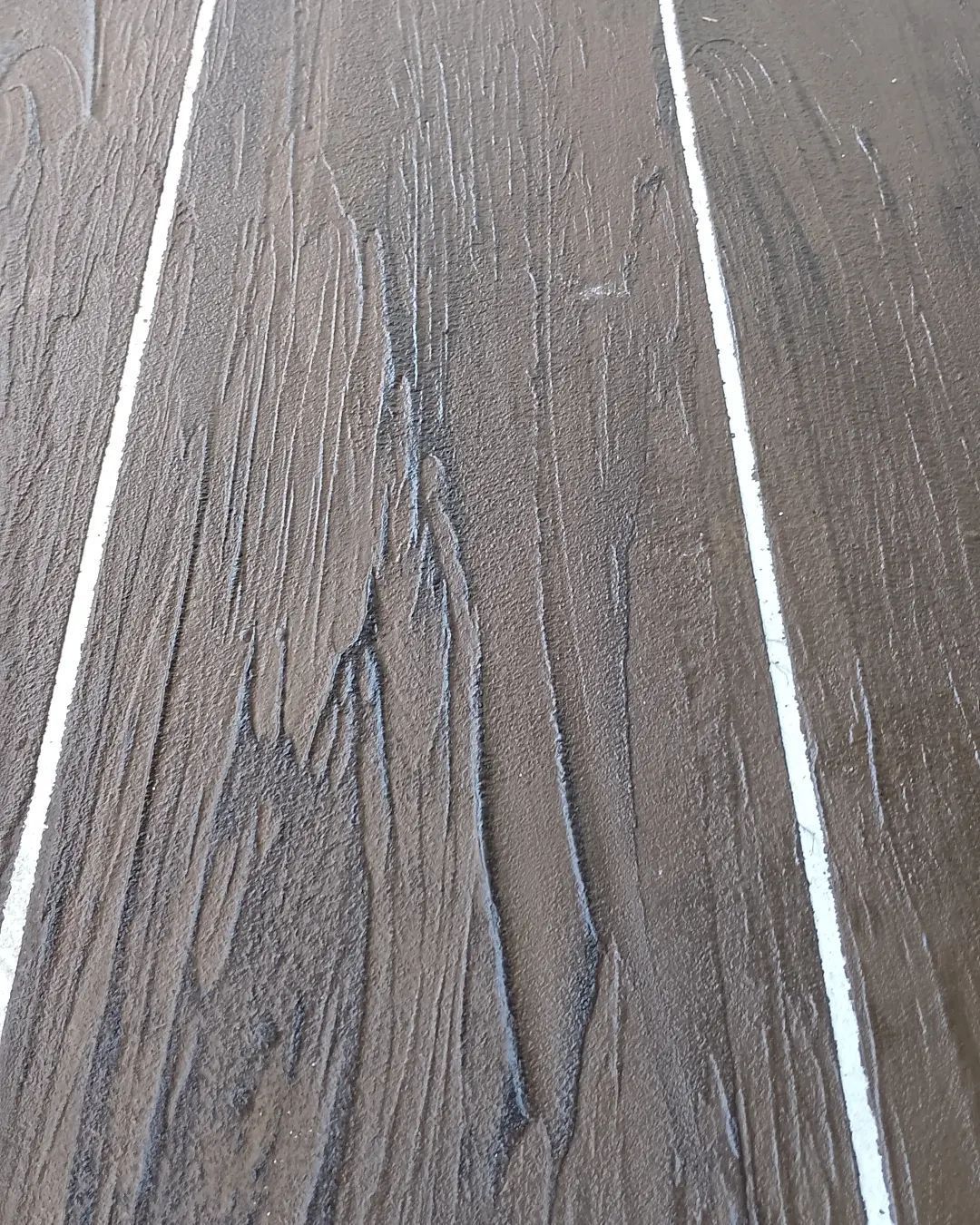 close up of concrete with a dark brown wood plant finish — Troys Concrete Overlays in Hillcrest, QLD