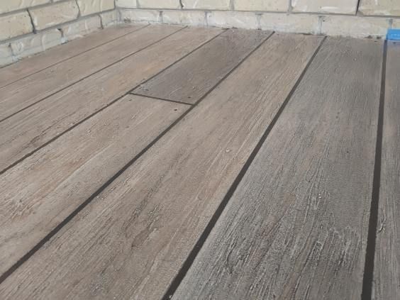 Weathered wooden deck boards beside a brick wall. — Troys Concrete Overlays in Hillcrest, QLD