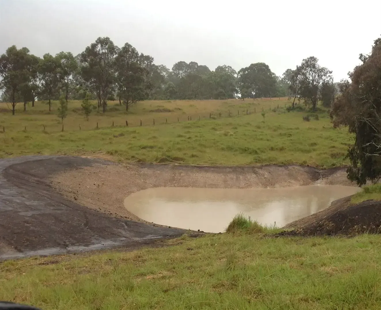 A Big Dirty Puddle in the Middle of a Grassy Field — S M & A J Gilbert Earthmoving in Mitchells Island, NSW