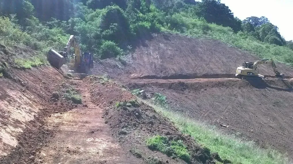 A Tractor is Driving Down a Dirt Road in the Woods Slowly — S M & A J Gilbert Earthmoving in Mitchells Island, NSW