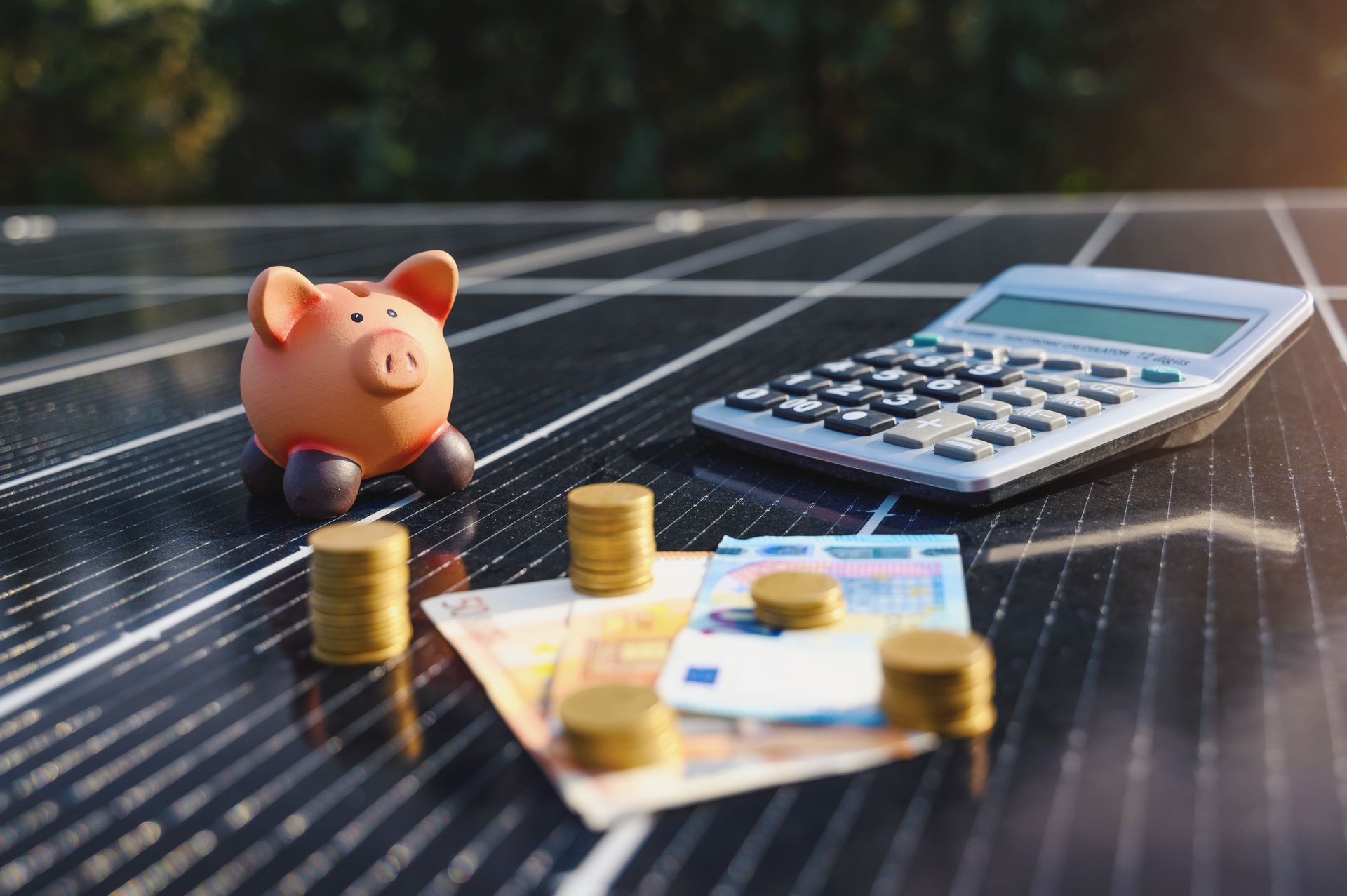 Piggy bank, coins, calculator, and euro bills on solar panels, suggesting savings or energy costs