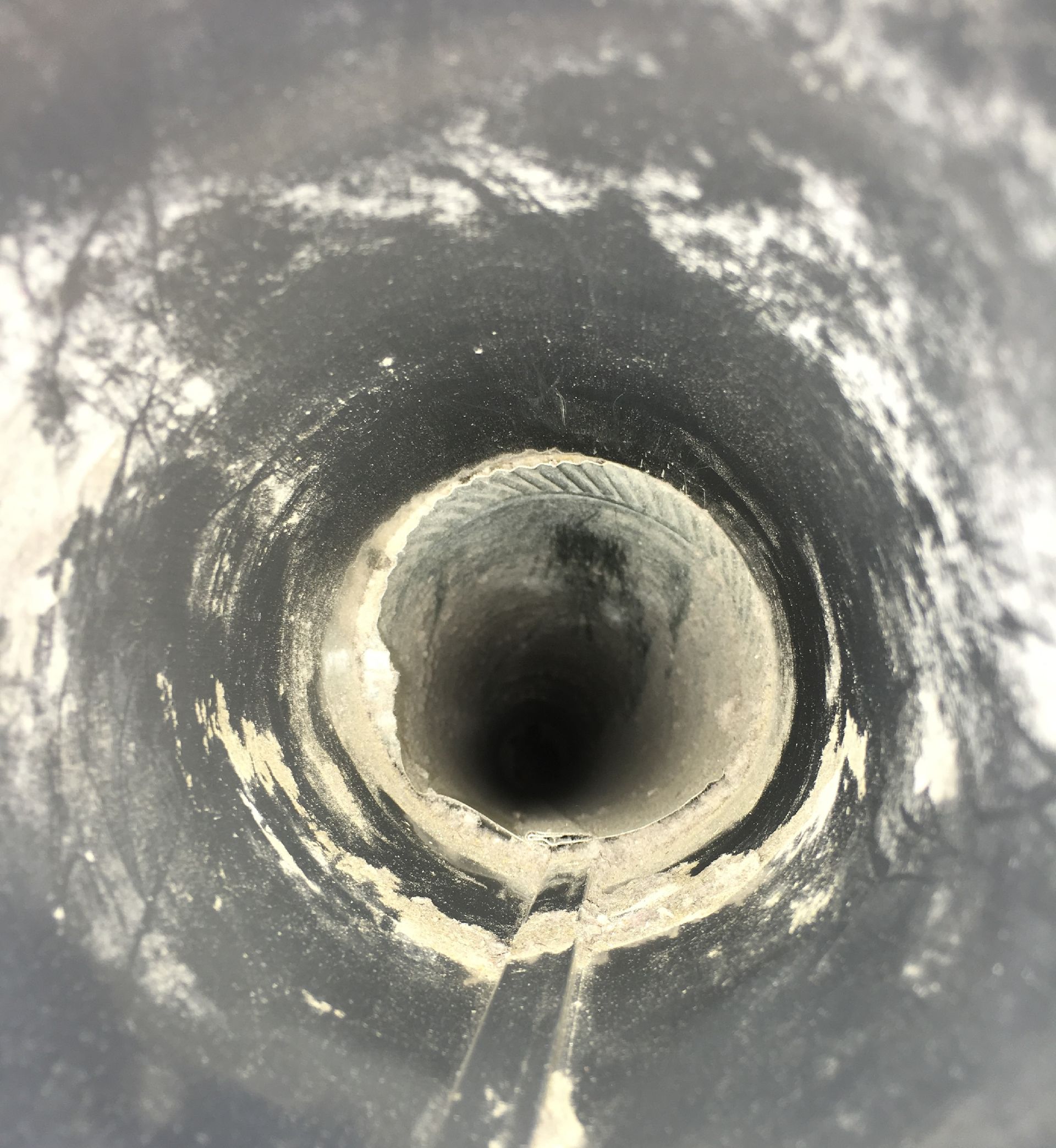 Inside a dark cylindrical pipe, looking down into a round tunnel with a bright opening