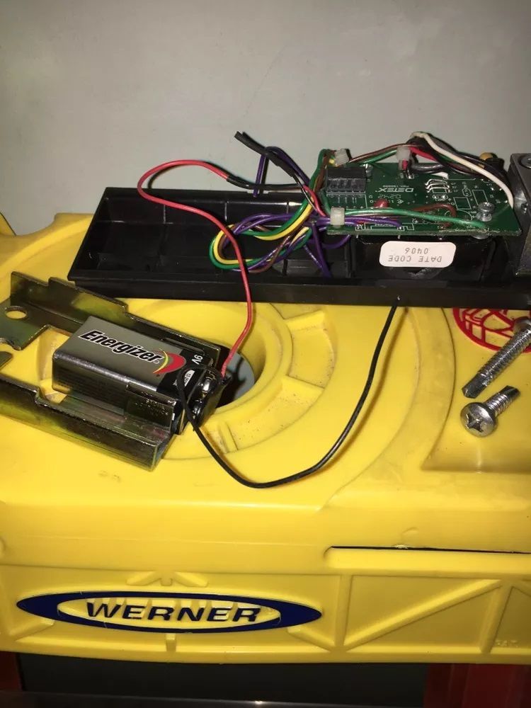 A yellow toy snow blower with wires coming out of it