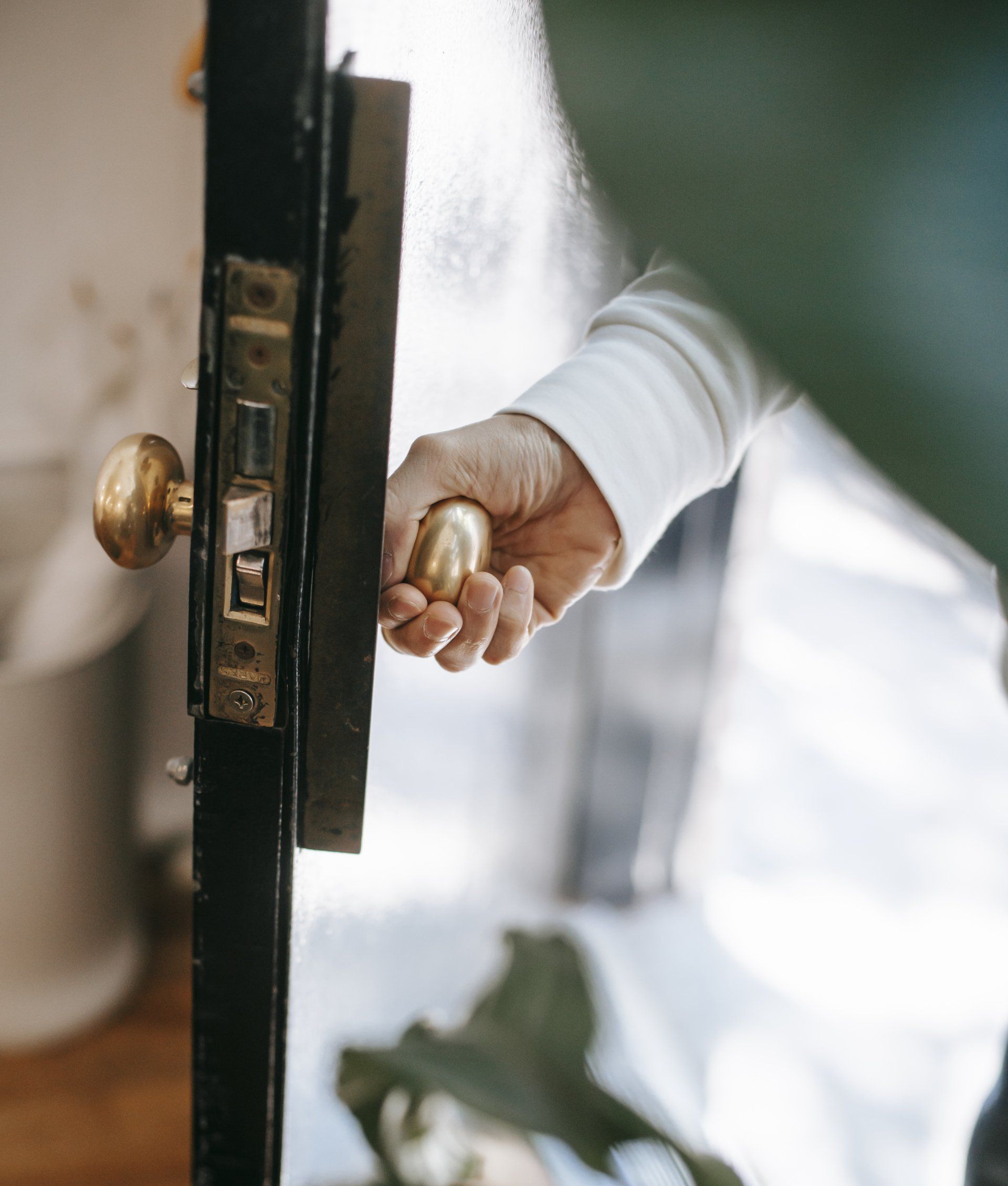 A person is opening a door with a brass handle