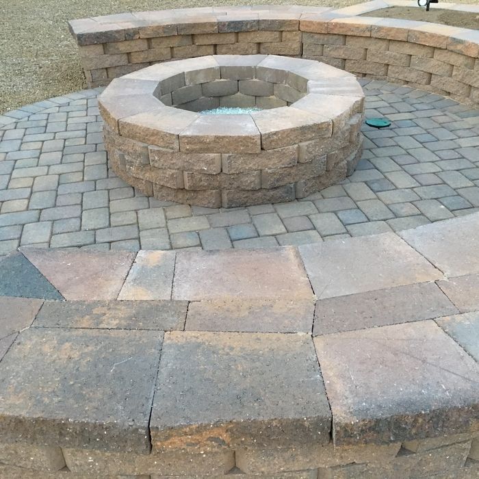 An outdoor fire pit with a paver sidewalk around it