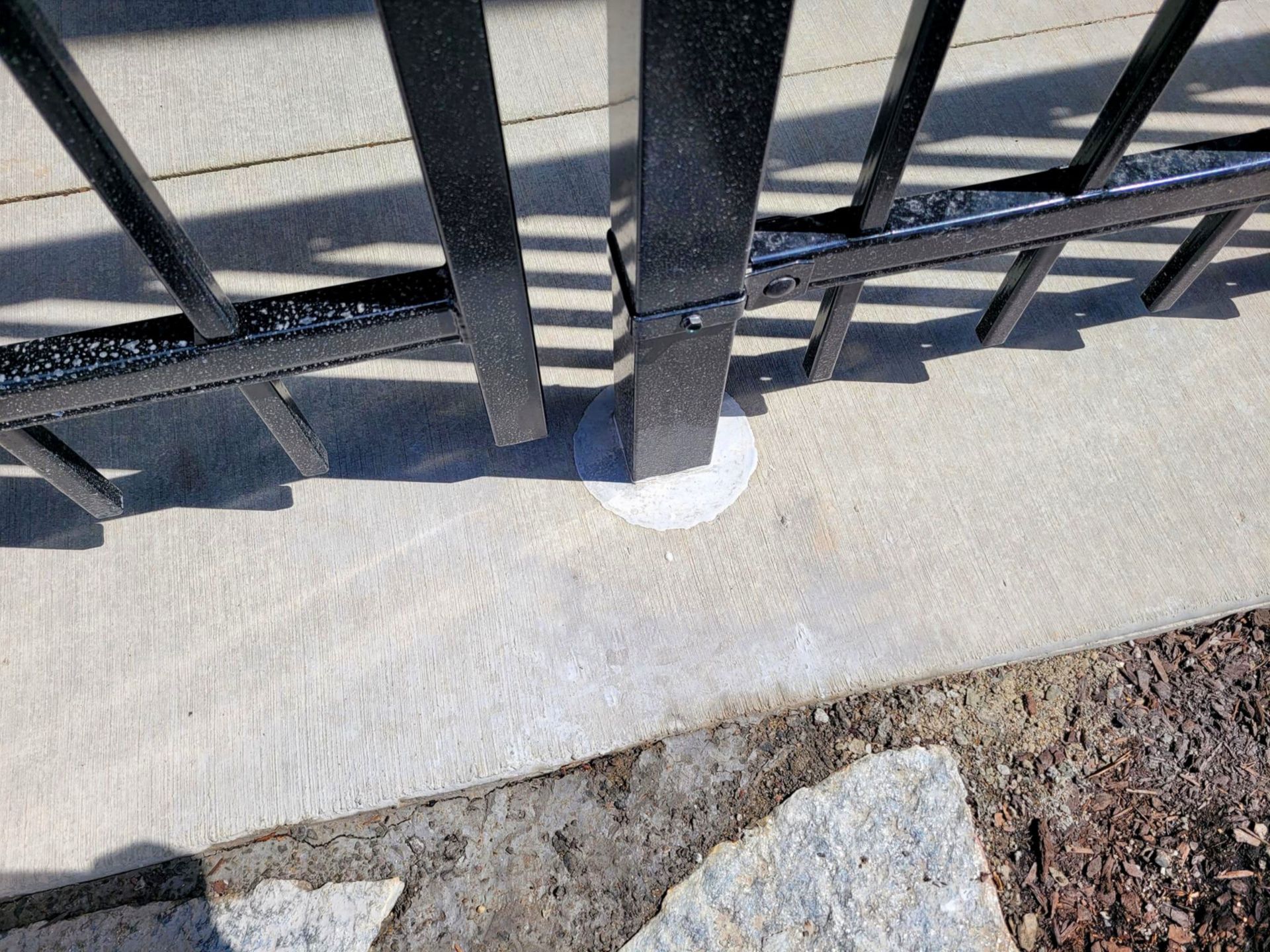 Black metal fence posts anchored in concrete.
