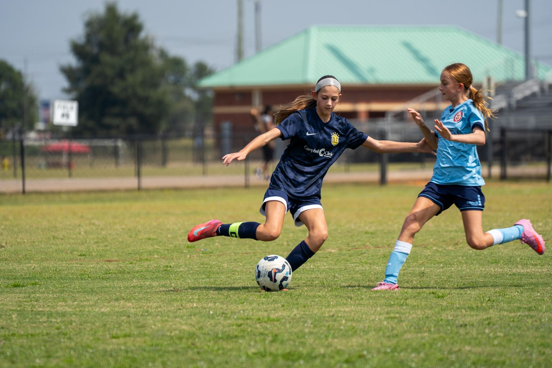 Two soccer players for Olé FC in blue uniforms playing soccer