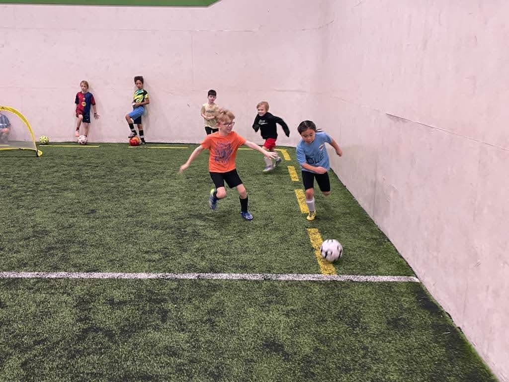 Children playing soccer on an indoor field at the Olé FC Winter Break Indoor Clinic