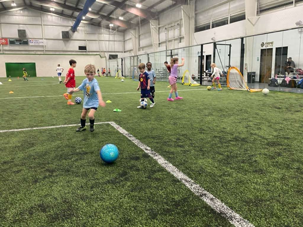 Children playing soccer on an indoor field at the Olé FC Winter Break Indoor Clinic
