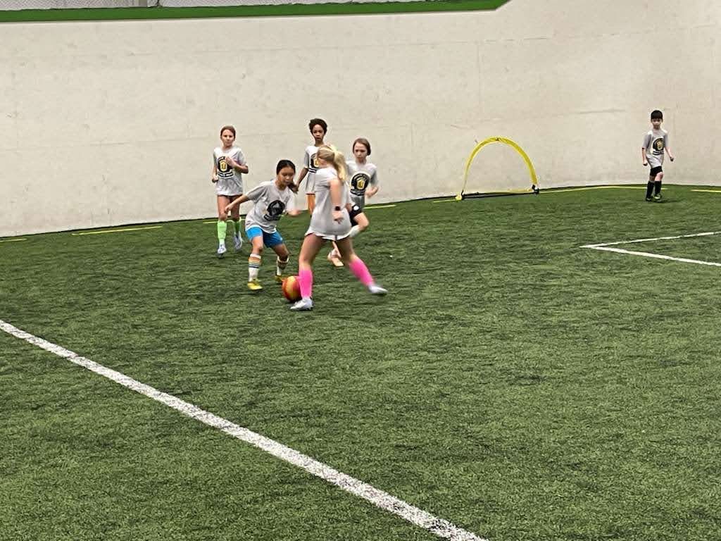 Children playing soccer on an indoor field at the Olé FC Winter Break Indoor Clinic