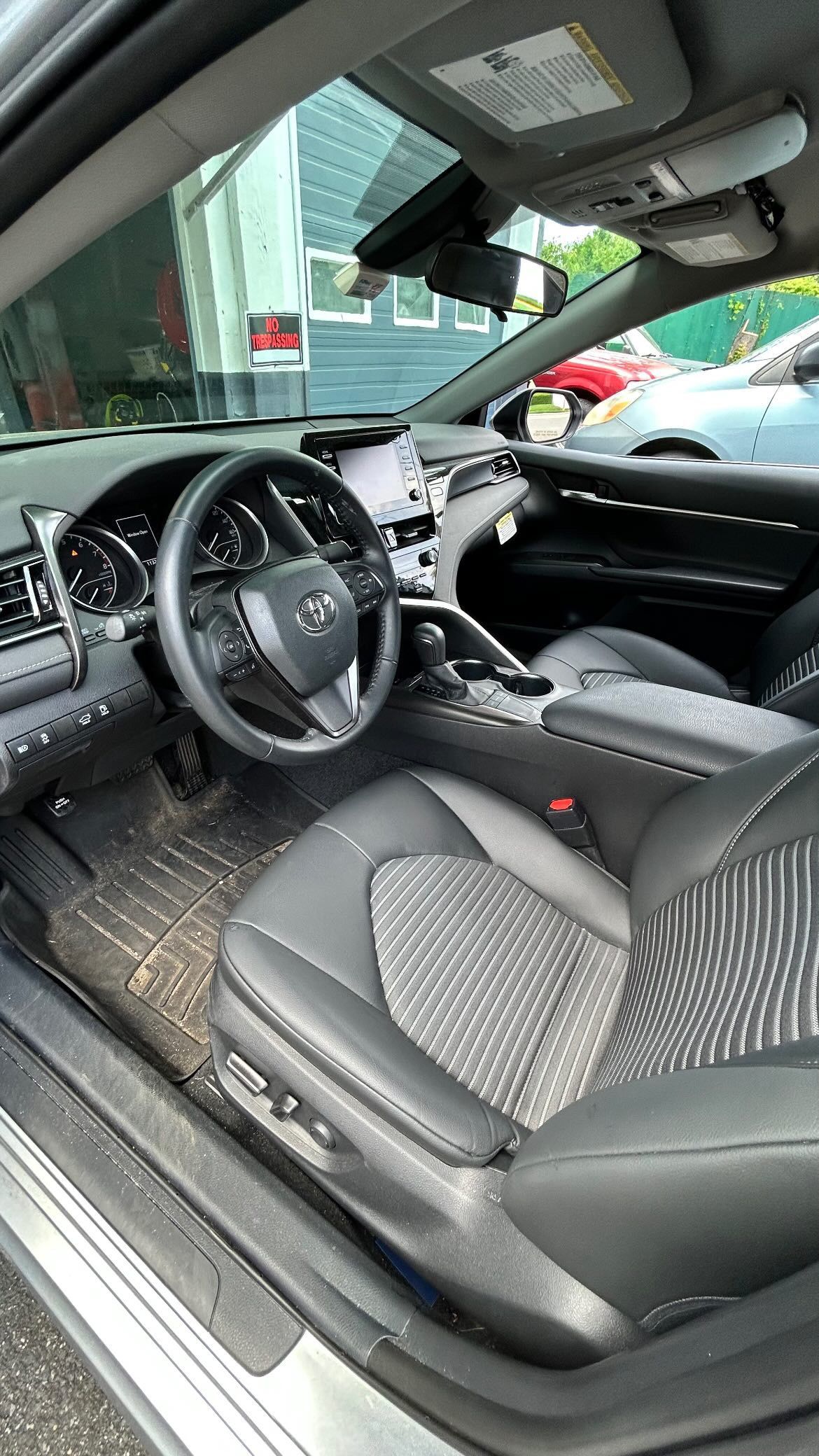 The interior of a car with the door open and the steering wheel visible.