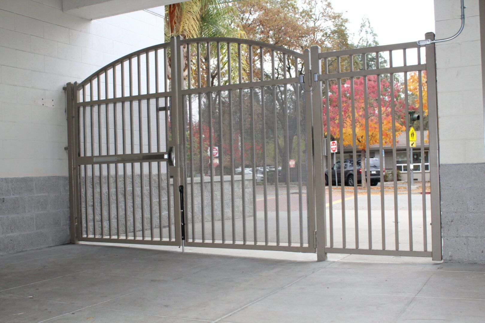 A metal gate is open to a parking lot