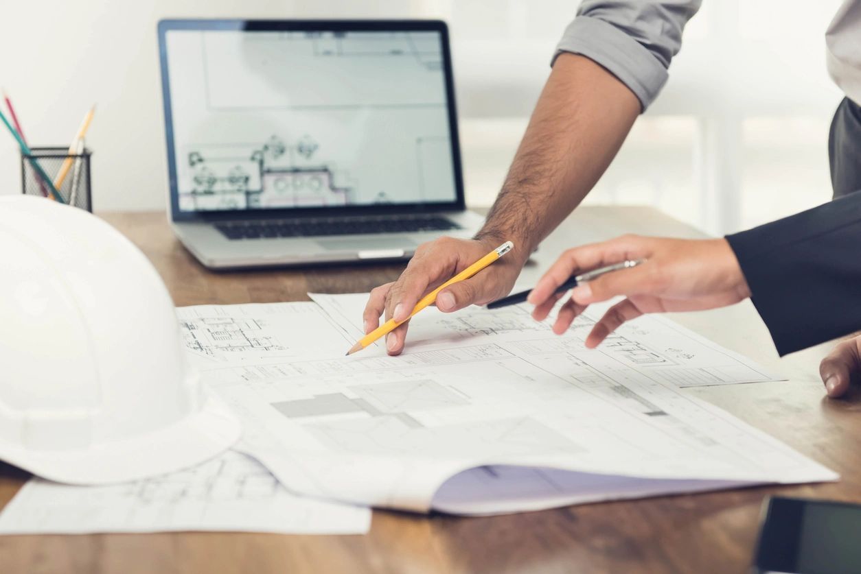 A couple of people are sitting at a table looking at a blueprint.