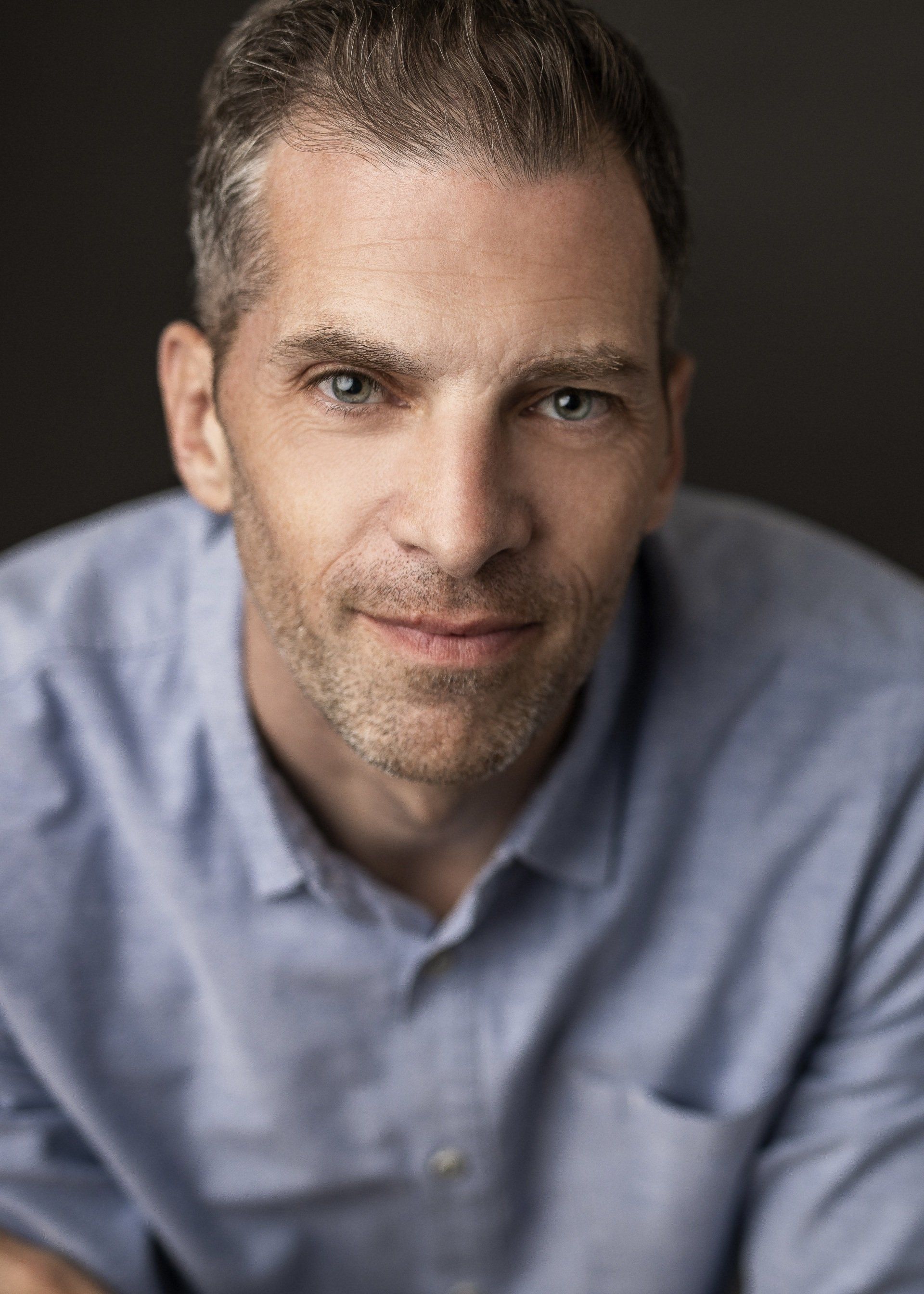 Man in a blue shirt looking directly at the camera with a slight smile.