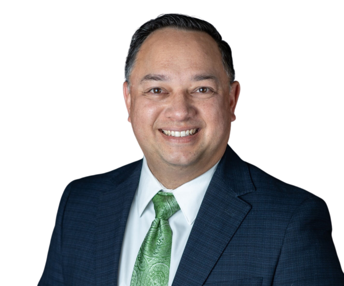 Man in dark suit and green tie smiles at the camera.