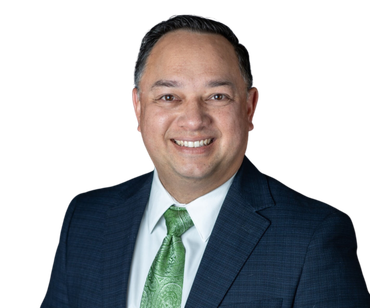 Man in dark suit and green tie smiles at the camera.