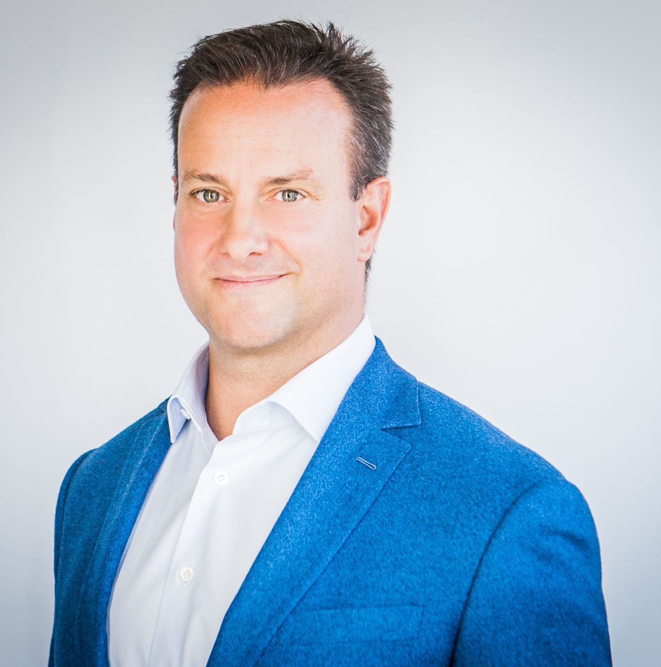 Man in blue blazer and white shirt smiles, headshot.
