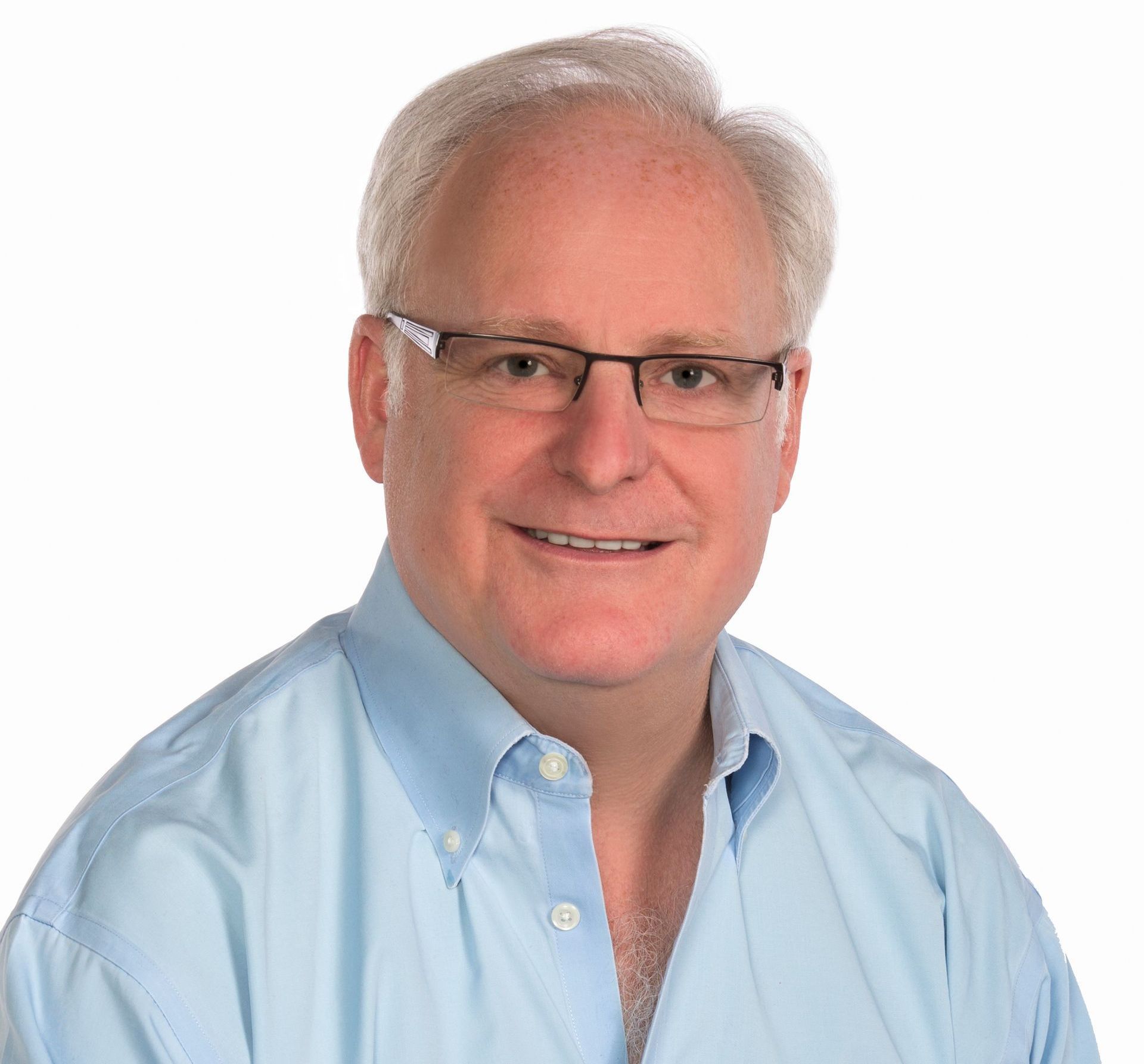 Man in blue shirt, glasses, smiles at camera.