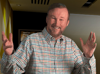 Man in plaid shirt smiling, gesturing with hands. Indoor setting.