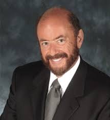 Man with a reddish beard and a suit smiles.
