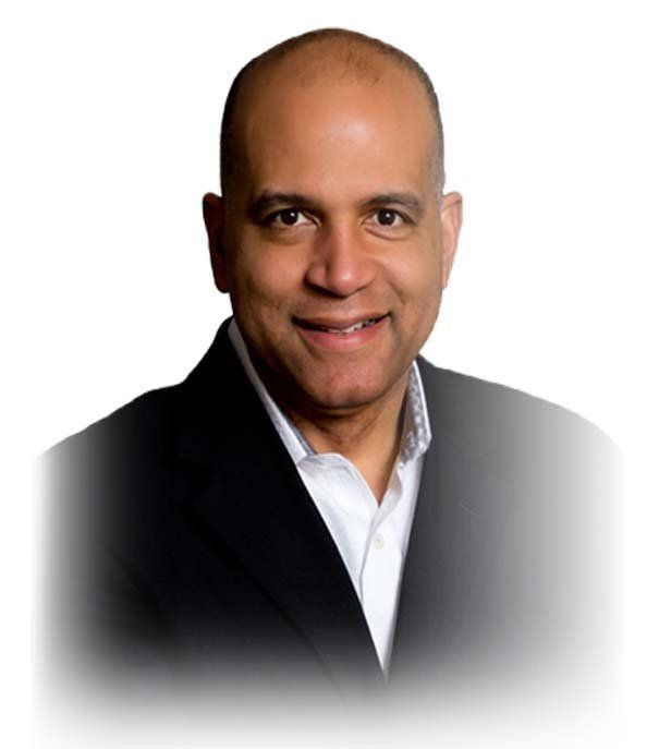 Man in a suit smiles, soft lighting.