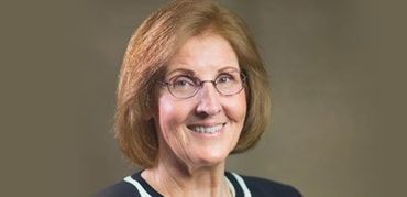 Woman with glasses smiles; black and white striped neckline.