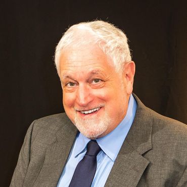 Man in gray suit smiles, looking at the camera.
