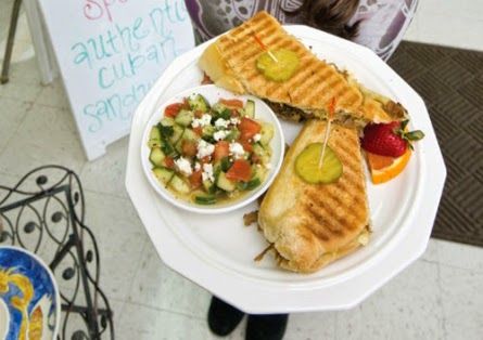 Two grilled sandwiches and a salad on a white plate at an outdoor café table