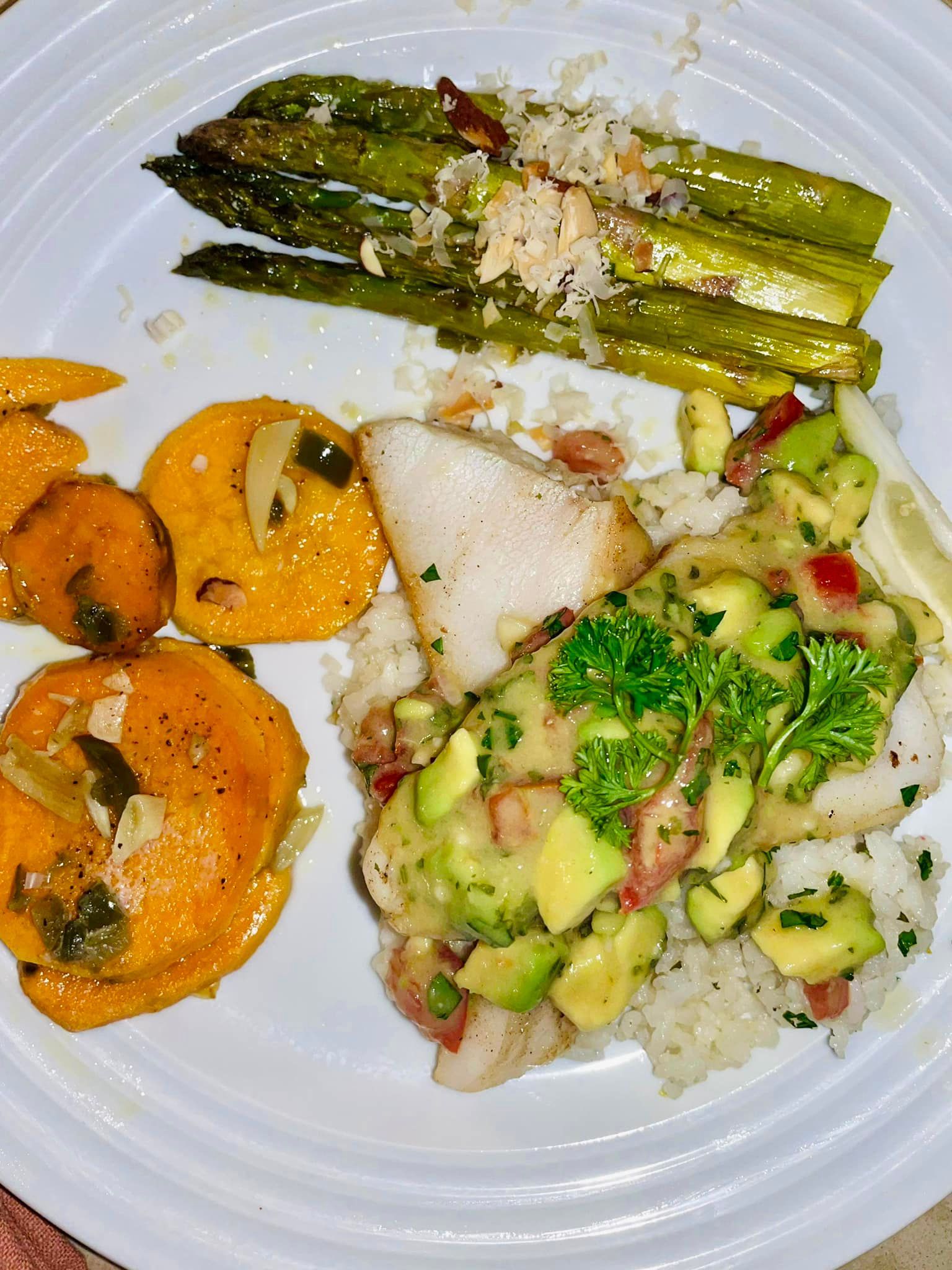 Plated seafood and vegetables: asparagus, zucchini, orange slices, and a fish fillet with rice.