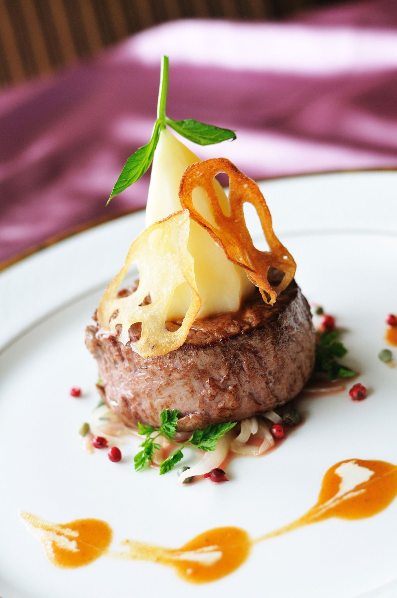 Plated gourmet steak topped with cheese and herb garnish, drizzled with sauce on a white plate
