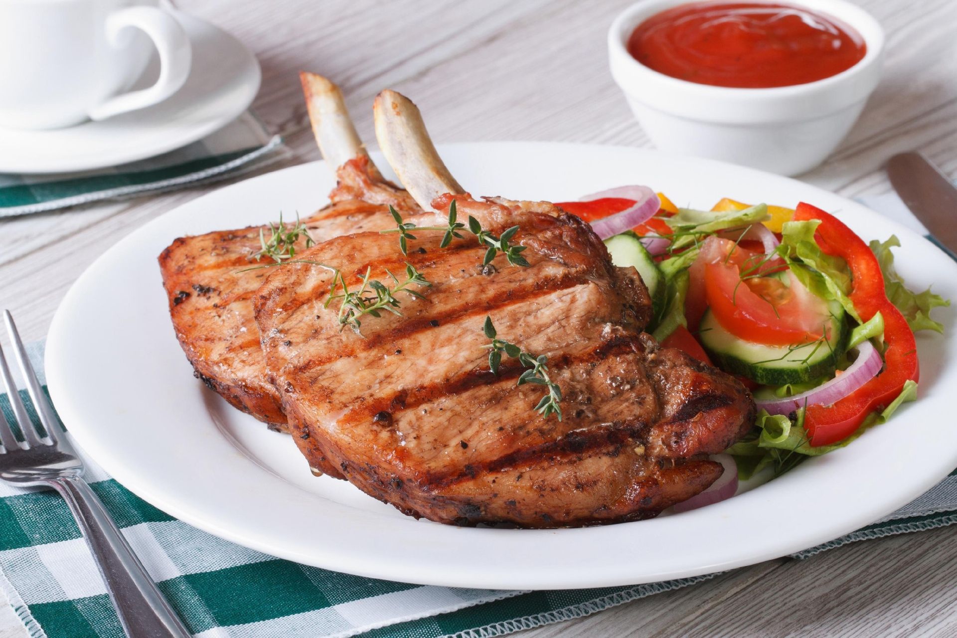 Grilled steak with tomato and onion salad, served with sauce on a white plate