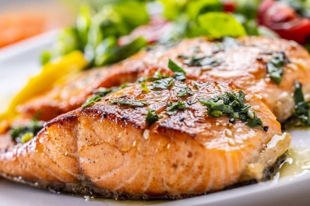 Grilled salmon fillet with herbs and lemon on a white plate