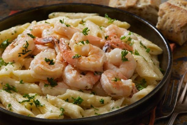 Shrimp pasta in a skillet, topped with herbs and a creamy sauce