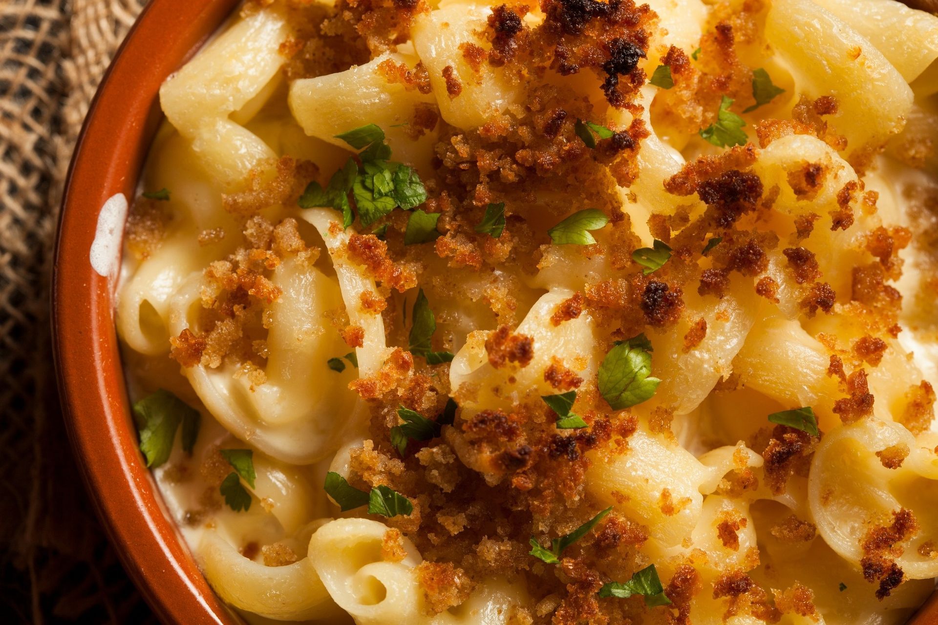 Close-up of macaroni and cheese topped with crispy breadcrumbs and chopped green onions in a bowl