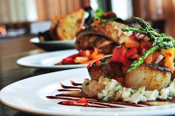 Plated gourmet fish with rice and vegetables, garnished with herbs and sauce on a dining table.