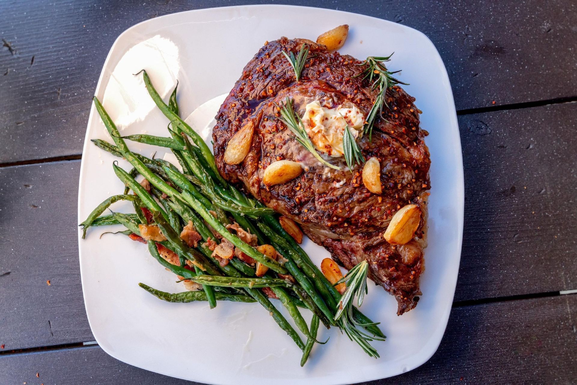 Grilled steak with garlic and herbs, served with roasted asparagus on a white plate