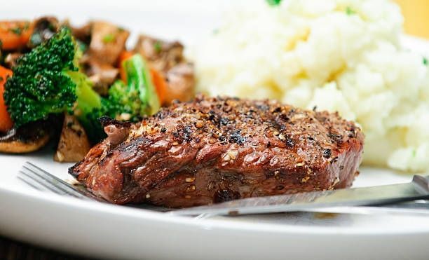 Grilled steak with broccoli, cauliflower, and vegetables on a white plate