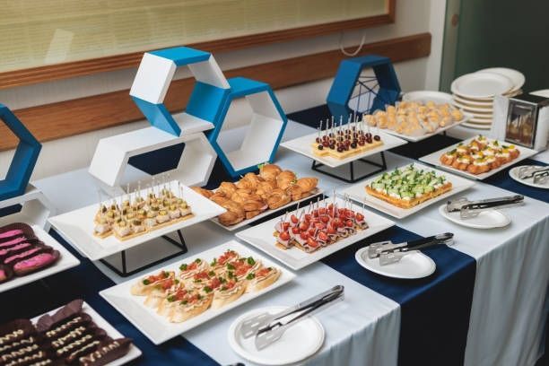 Buffet table with assorted appetizers on white platters, set on a dark tablecloth in a banquet room
